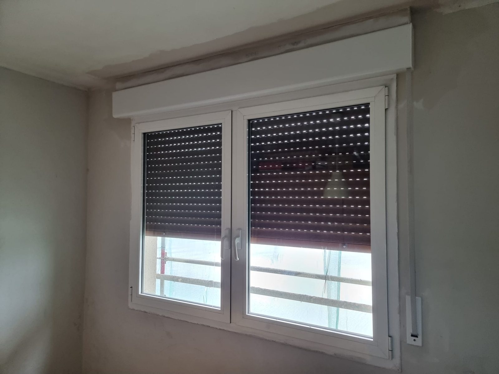 Ventana blanca de dos hojas con persianas oscuras y cajón compacto